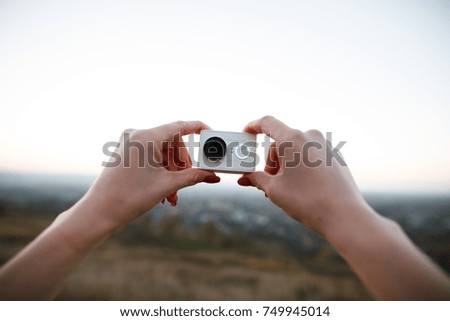 human hands holding an action camera on the sunset background