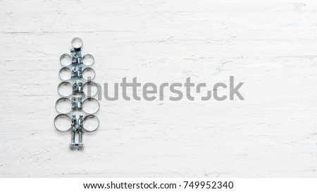 Hose clamps and nuts and bolts decorated as christmas tree on a white wooden background. Christmas greeting card and Happy new year greeting card concept. Top view with copy space for your text