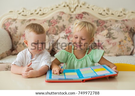 Little Girl Reading Book to Brother at Home