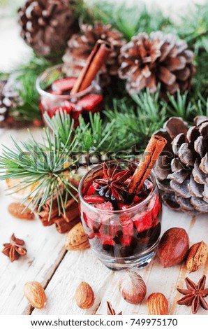 A glass of hot mulled wine for the new year with ingredients for cooking, nuts and Christmas decorations, a Christmas card, selective focus, space for text, a low key