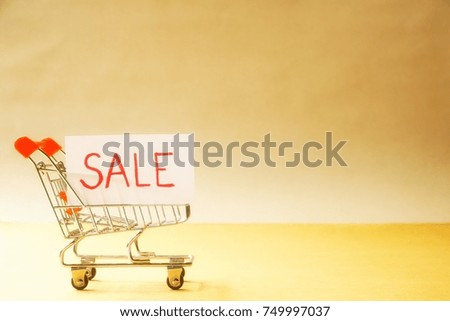 Shopping cart with paper "SALE" isolated on brown background. For create brochure or leaflet.