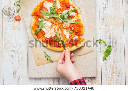 Neapolitan pizza with tomatoes, mozzarella, arugula on a light stone and a wooden background. yummy.)
Flat lay, top view. Food photo with hands.
