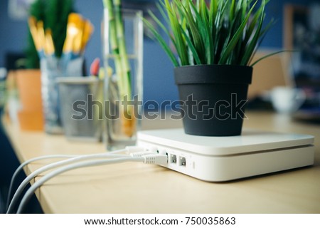 Closeup of a broadband router, plant in pot is placed on router, with a blur background.
