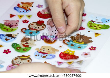 Kid is gluing a sticker on applique