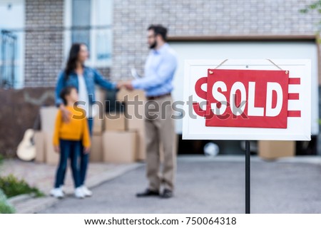 realtor making deal with single mother with sold signboard on foreground