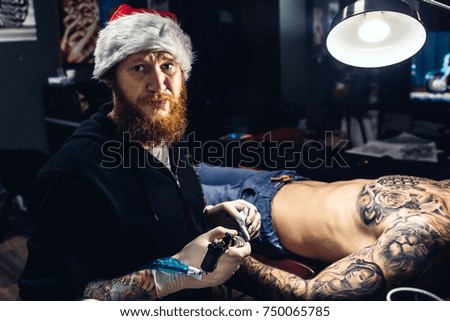 Artist man doing tattoo on the body of the man