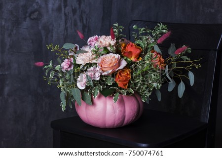 Autumn floral bouquet in pumpkin vase on black chair