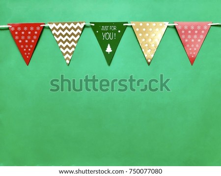 Closeup colorful Christmas triangle flag rail set on green background.The concept of Xmas celebration, Christmas party,greeting season,Christmas decoration.Top view with Copy space.Selective focus.