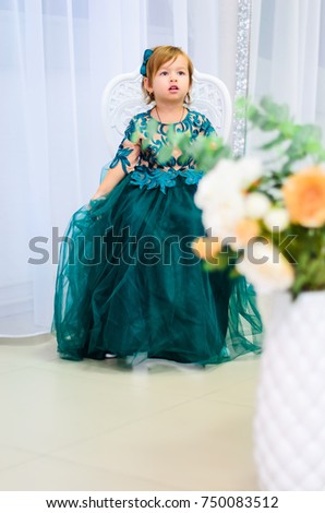 A little girl dressed in a splendid dress . Shooting in the Studio, elegant interior in bright colours . 