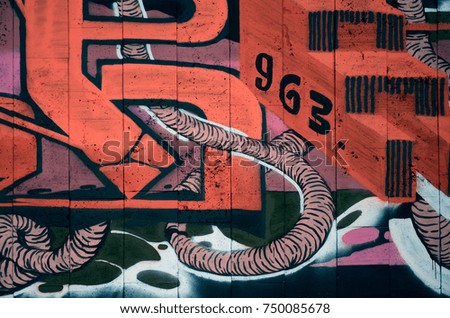 A fragment of detailed graffiti of a drawing made with aerosol paints on a wall of concrete tiles. Background image of street art in warm red color tones