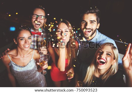 Group of people having a party, blowing confetti 