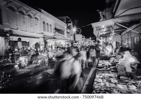 several people walking in the night market on old town road, motion blurred in purpose