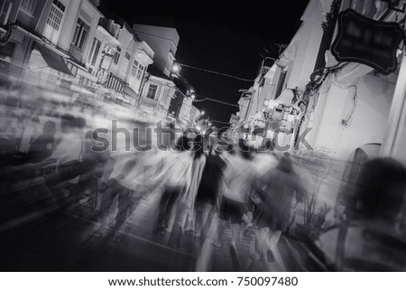 several people walking in the night market on old town road, motion blurred