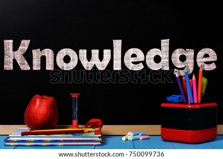 Text Knowledge on black chalkboard with school accessories