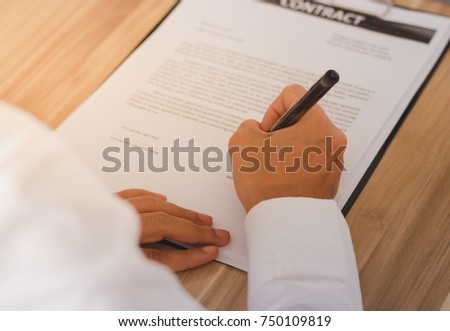 Businessman signing paperwork.