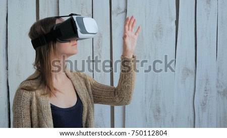Young woman using Virtual Reality Glasses. Virtual reality mask. VR. White wooden background. Future and technology concept