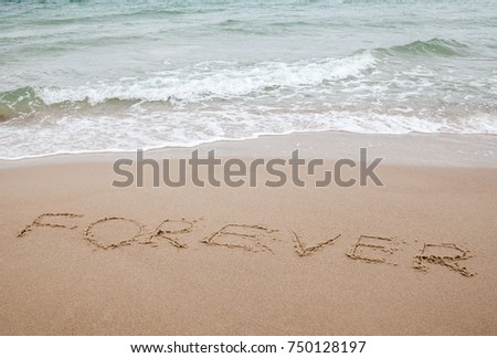 Word forever written on the sand near the sea. Sea waves rolling onto the beach.