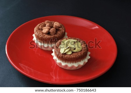 delicious cupcakes on a black background with almonds and pumpkin seeds on top