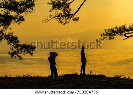 silhouette two man asia with backpack taking a photo on the top of mountains ,soft focus