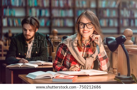 Portrait of two successful students casual stylish, boy and girl in library reading hall, evening time, education concept