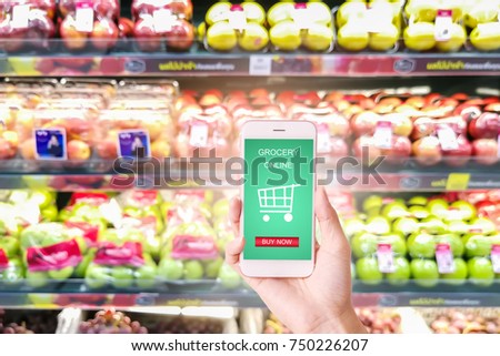 woman hand  holding mobile with grocery online on screen with blur supermarket background