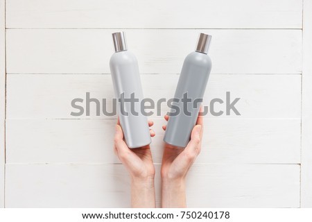 The woman chooses one of the two shampoos in the bottle. The concept of beau.ty and choice of cosmetics. Top view woman hands with bottles Royalty-Free Stock Photo #750240178