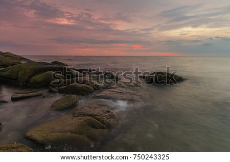 Rocks on the sea shore with the Sun on Larn Hin Kaw Hadmarrumphung beach in the background