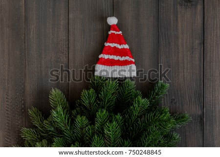 Christmas fir tree branches and santa clause hat on dark rustic wooden background with copy space for text