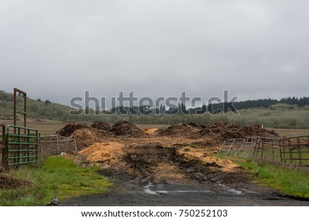 Agriculture Driveway: The entrance to the field has mounds of dirt and bark chips. Royalty-Free Stock Photo #750252103