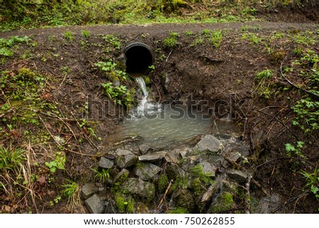 Drainage Culvert: A culvert directs water under the path. Royalty-Free Stock Photo #750262855