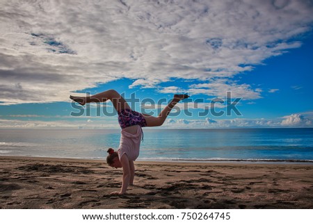 Teenager girl is doing sport at the beach on the Azores in front of the Atlantic and the blue sky