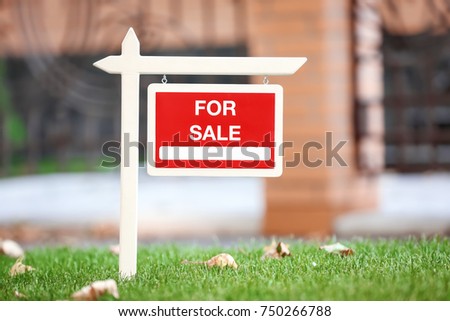 "For sale" sign on lawn near house