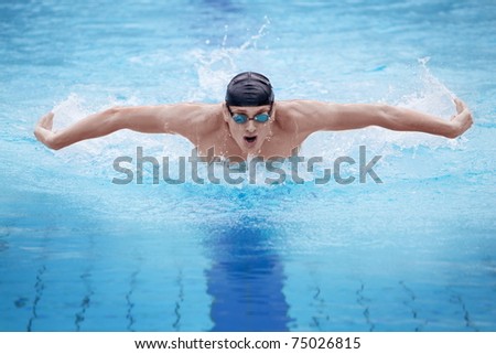 dynamic and fit swimmer in cap breathing performing the butterfly stroke Royalty-Free Stock Photo #75026815