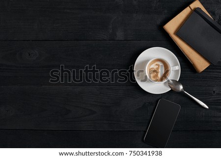 Smartphone with notebook and cup of coffee on wooden background. Cell phone with writing set with espresso