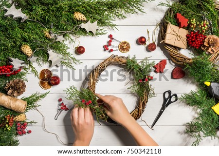 Christmas handmade diy background. Making craft xmas wreath and ornaments. Top view of white wooden table with female hands.