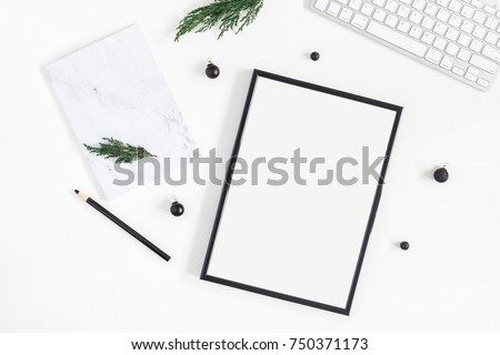 Christmas desk. Black frame, keyboard, marble notebook and christmas tree branches on white background. Flat lay, top view, copy space