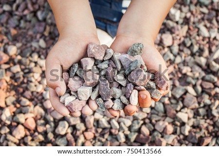Child holding small colorful stones in little hands. Concept of game money, valuable resource Royalty-Free Stock Photo #750413566