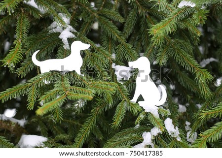 New Year greeting card with paper dog figures on fir tree green branches with snow.