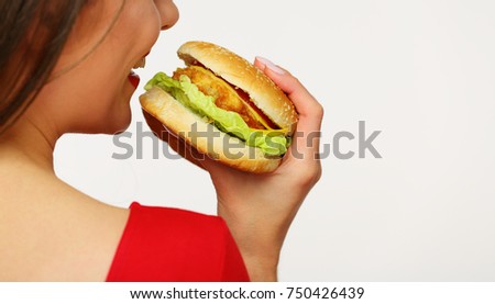 Girl standing back bites burger close up portrait.