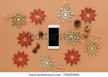 Christmas decoration, wooden snowflakes ornament on brown background, top view. Online shopping on smartphone with copy space on screen. Preparing for winter holidays concept.