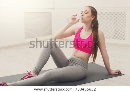 Fitness woman drinking water at gym on white background