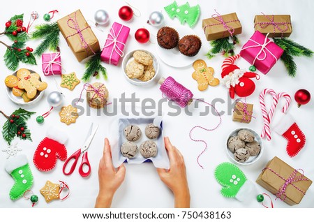 Christmas background with gifts, cookies, Christmas decoration and woman's hands holding cookies. toning. selective focus
