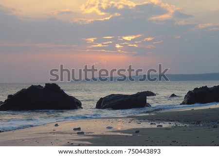 Landscape picture of the sun setting on the beach with three rocks in Kenting, Taiwan