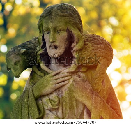 A fragment of ancient figure of Jesus with the lambs on the neck in the old cemetery as a symbol of a good pastor, love, intercession and salvation of mankind after death in the kingdom of eternity.