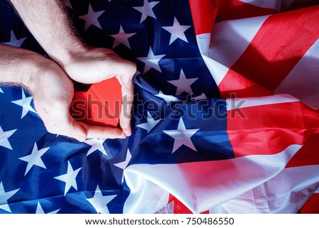 In hands lies the little heart. American flag background.