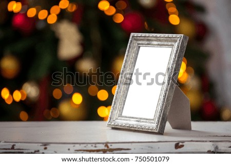Empty blank photo frame on the table in christmas decorated defocused background with toys and lights
