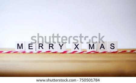 White wood letters make wording is Merry Christmas with red and white ribbon on the wood table with white background. The picture concepts are celebrated, banners, festival, New Years, party.