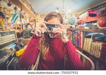 beautiful young girl taking a photo in a vintage shop by her vintage camera