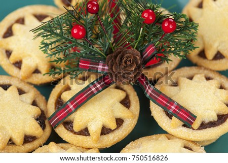 Christmas acorn and tartan motif with berries on top of a plate of freshly baked star topped mince pies