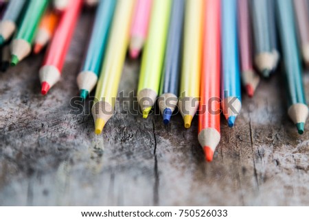 Colorful pencils on the distressed wooden table background 